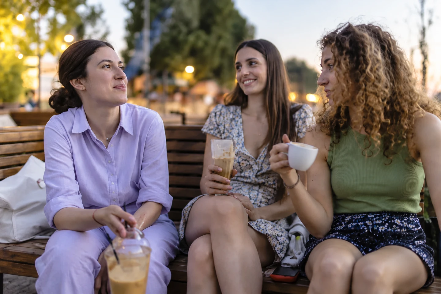 Three friends talking over drinks at an outdoor cafe