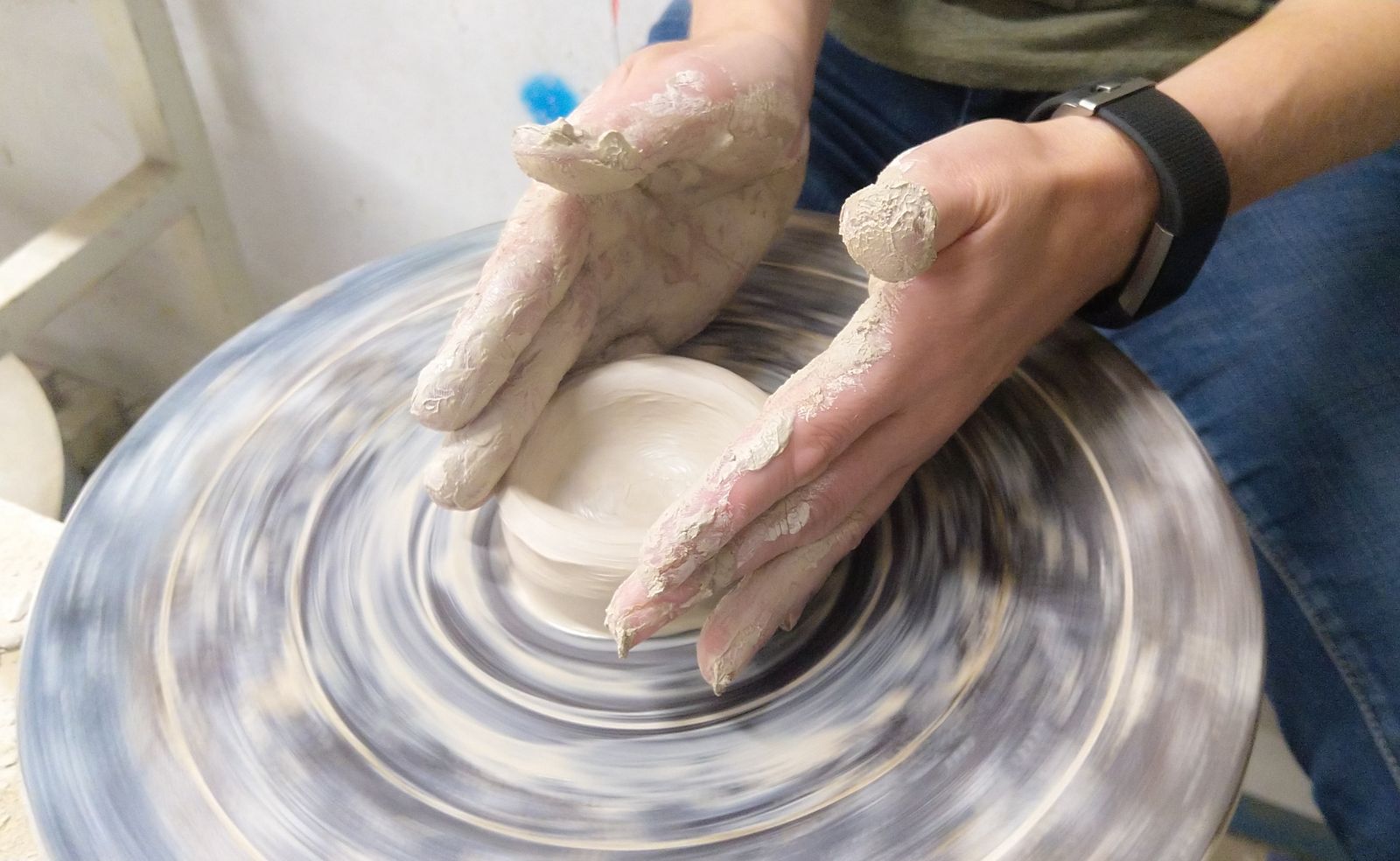 Hands shaping clay on a pottery wheel, used for the photo-question example below