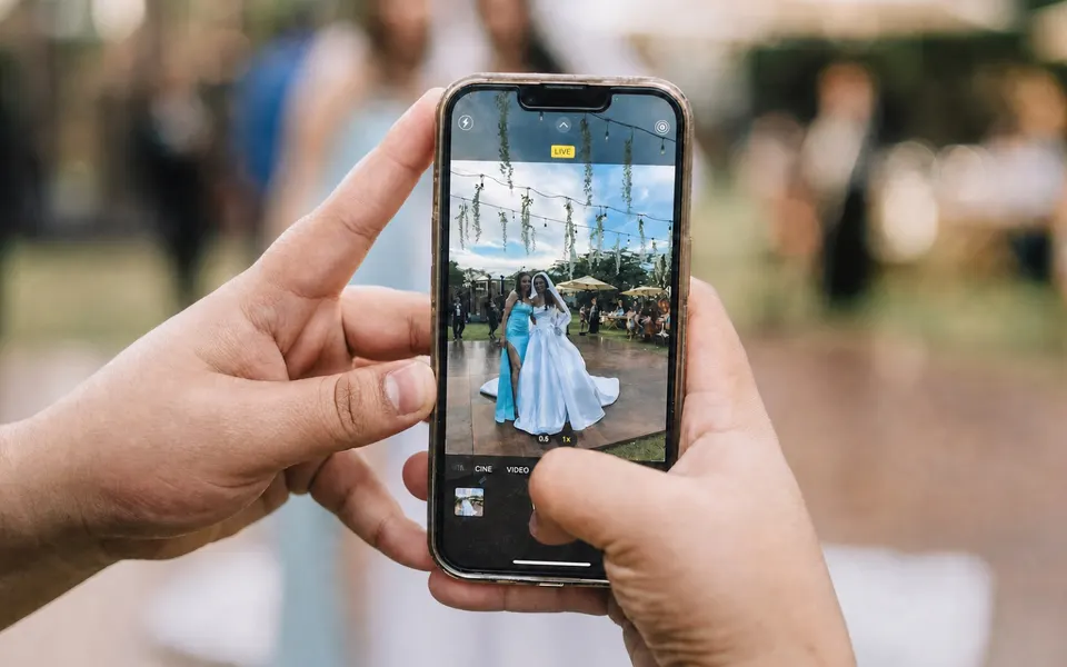 A wedding guest using a phone to photograph the bride during the reception