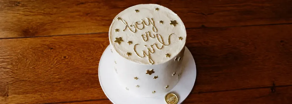 White baby shower cake decorated with gold stars and Baby Joy lettering