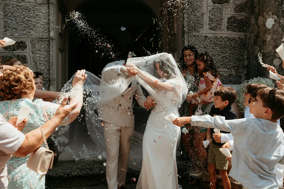 Newlyweds laughing beneath confetti after their wedding ceremony