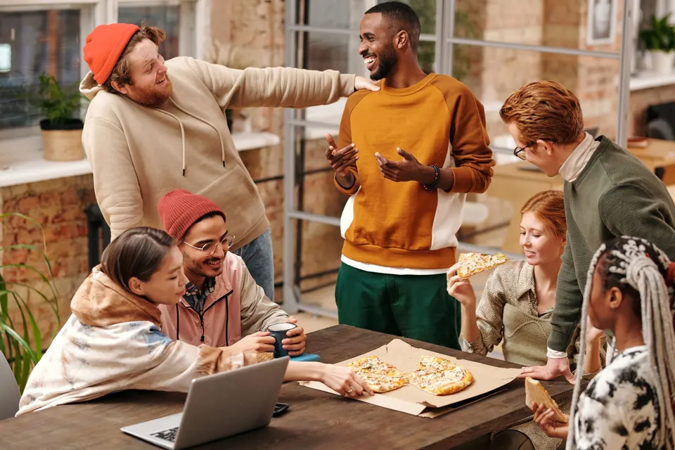 Friends laughing and sharing pizza at a gathering