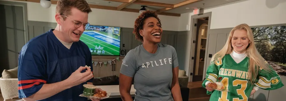 Three friends laughing together at a home party